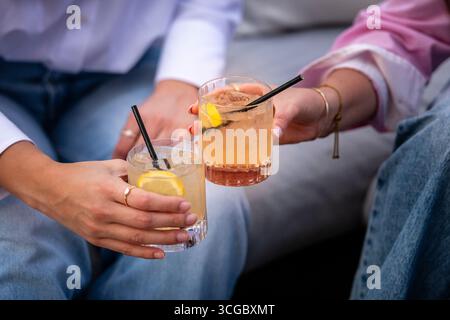 Cocktails Sommerzeit Großbritannien, Nahaufnahme von zwei jungen Frauen, die Getränke halten Stockfoto