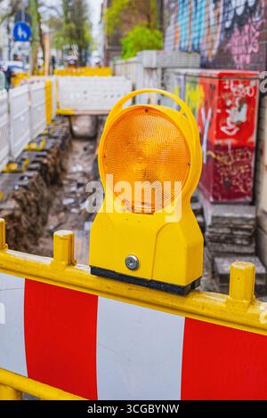 Leuchtend orange Bauschranken mit Lichtern an der Flurstraße während des Baus Stockfoto