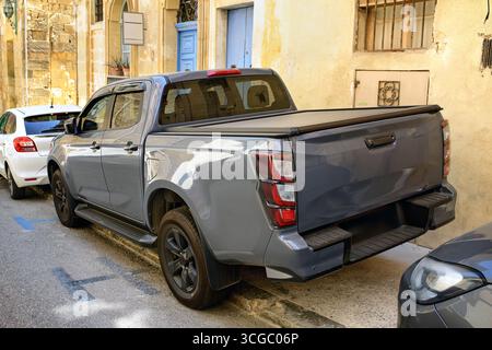Pick-SUV mit geschlossener Ladefläche, die auf einem schmalen Bürgersteig in der Nähe eines Hauses geparkt ist. Ansicht des hinteren Seitenwinkels mit Schlussleuchten, Rädern und Frontspiegel. Stockfoto