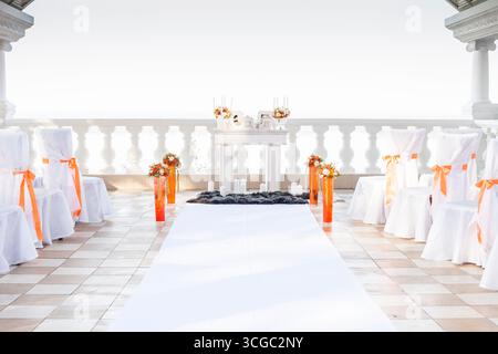 khabarowsk, russland, 20.10.2013 Hochzeitszeremonie im Freien mit weißen Stühlen, orangefarbenen Bändern, Blumenarrangements und einem Gang-Läufer auf einem Balkon. Stockfoto