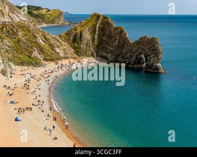 Blick auf Touristen aus einem hohen Winkel am sonnigen Durdle Door Beach, Dorset, England Stockfoto