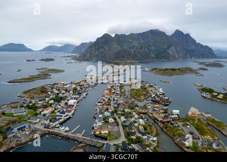 Blick von der Drohne auf Henningsaer, ein malerisches Fischerdorf, eingebettet in die zerklüfteten Berge und das ruhige Wasser der lofoten-Inseln in norwegen Stockfoto