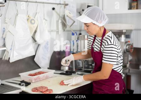 Kochen halbfertiger Produkte - Mädchen bereitet Fleischkoteletts mit speziellen Geräten zu Stockfoto