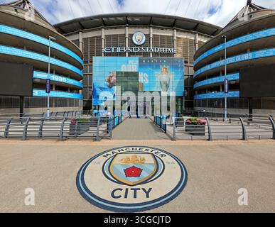 Weitwinkelansicht des Haupteingangs zum Etihad Stadium, Heimstadion des MCFC, im Osten von Manchester, England, Großbritannien. Das Manchester City Wappen ist deutlich sichtbar Stockfoto