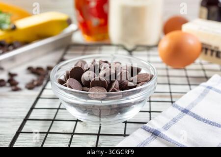 Ein Blick auf eine Glasschale gefüllt mit halbsüßen Schokoladenstückchen, in einer stillen Umgebung. Stockfoto