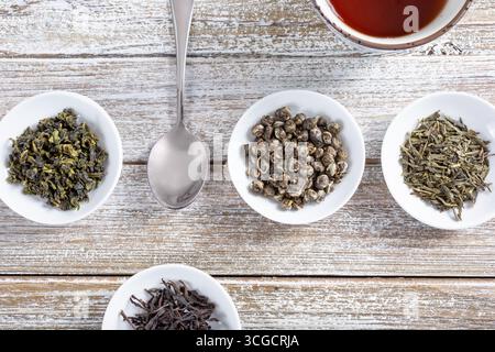 Ein Blick von oben nach unten auf mehrere kleine Untertassen mit einer Vielzahl von getrockneten losen Teeblättern. Stockfoto