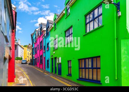 Eine farbenfrohe Wohnstraße mit rosa, türkisfarbenen, roten und lindgrünen Häusern in der Küstenstadt Kinsale, County Cork, Irland. Stockfoto