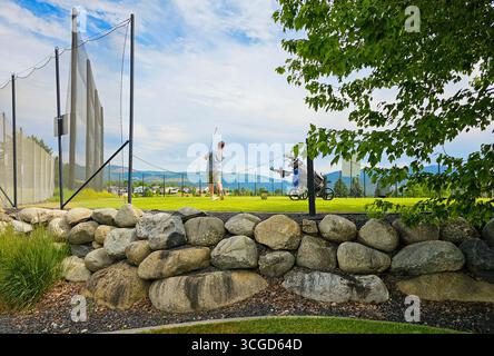 Ein junger Mann hält das Ziel eines Golfschwungs auf einem vorstädtischen Golfplatz. Stockfoto