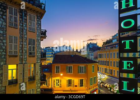 Fensterblick von einem Zimmer im oberen Stockwerk mit Blick auf Hotels und Cafés in der Innenstadt von Nizza, Frankreich, in der Dämmerung entlang der französischen Riviera Stockfoto