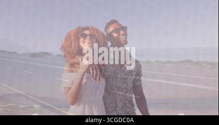 Lächelndes Paar mit Sonnenbrille auf der Küstenstraße, mit Läufern in Sportjacke, die Leitplanke Stockfoto