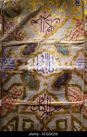 Türkei: Ein Detail aus einem talismanischen Hemd aus dem 16. Jahrhundert (Baumwolle, Tinte, Gold und Blattsilber), Kaiserliche Bekleidungsgalerie, Topkapi-Palast, Fatih-Viertel, Istanbul. Talismanische Hemden sind in der ganzen muslimischen Welt zu finden. Die Hemden sind mit Versen aus dem Quran, Namen Allahs und Propheten und mit Zahlen versehen. Es wird angenommen, dass die eingetragenen Namen dem Beförderer Schutz und Orientierung bieten können. Obwohl talismanische Hemden zum Schutz vor vielen Übeln getragen werden können, scheinen die meisten als Schild im Kampf zu dienen. Stockfoto