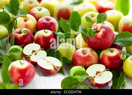 Frische rote und grüne Äpfel mit Blättern auf Holztisch Stockfoto