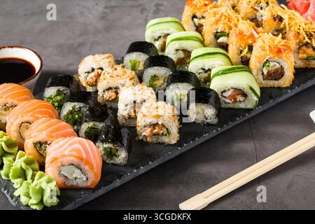 Verschiedene Sushi-Brötchen serviert auf einem Schieferteller mit Wasabi, Sojasauce und Ingwer Stockfoto