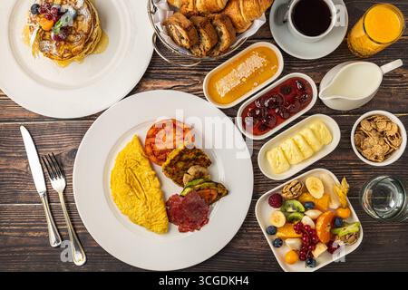 Köstliches Frühstücksset mit Pfannkuchen, Omelett, Croissants und Obst Stockfoto
