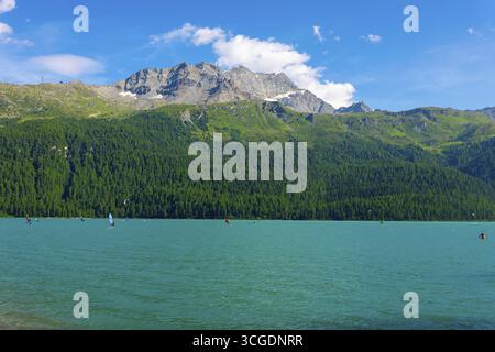 Windsurfen und Wingsurfen auf dem Alpensee Silvaplana an einem sonnigen Sommertag mit Berg in Silvaplana, Maloja, Graubünden, Schweiz Stockfoto