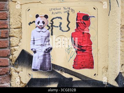 Zwei Figuren in Mänteln, ein Panda in weiß und eine schwarze Krähe in Rot. Street Art, Graffiti in Bologna, Italien. Stockfoto