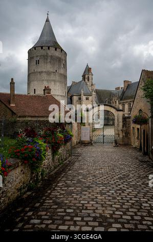 Foto des Eingangs zum Château de Châteaudun in Frankreich, eingerahmt von blühenden Blumen und dramatischen Sturmwolken darüber. Stockfoto
