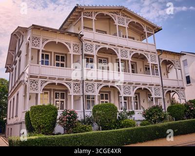 Göhren, Deutschland; 6. Juli 2025: Historische Rugener Seebad-Villa mit kunstvollen Holzveranden, klassischer Baltikum-Architektur, mit buxus-Garten Stockfoto