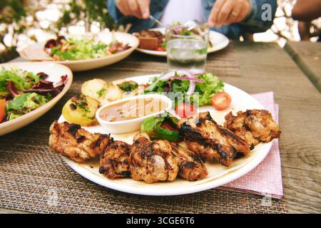Gegrillte Hähnchenflügel auf Teller mit frischem Salat und Gemüse Stockfoto