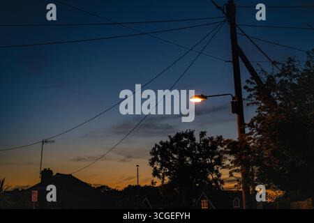 Crawley West Sussex. Silhouette viktorianischer Häuser mit Telegrafenmasten und Stromkabeln bei Sonnenuntergang Stockfoto