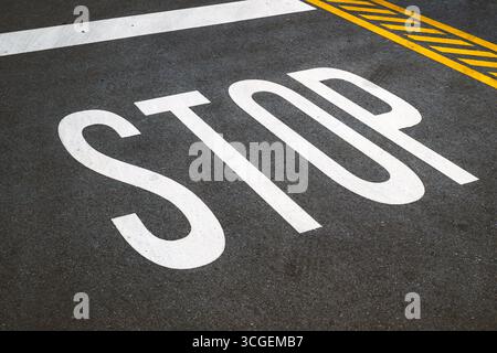 Weißes Stoppschild auf Asphalt, das Vorsicht und Pause symbolisiert. Selektiver Fokus. Stockfoto