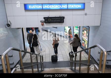 Reisende, die Koffer ziehen, laufen vom Bahnhof Euston in die U-Bahn nach London Stockfoto