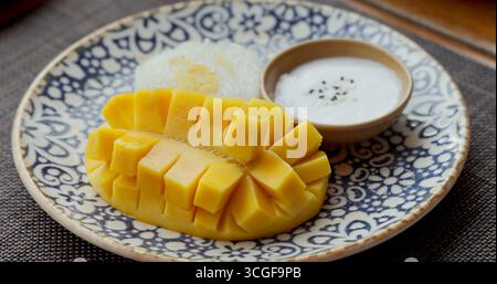 Dessert mit Mango-Klebestreifen auf gemustertem Teller, traditionelle thailändische Küche Stockfoto