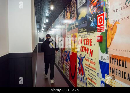 Madrid, Spanien, Tourist man, von hinten weg, Hotelflur, mit Vintage-Plakaten an der Wand Stockfoto