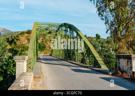 Vom Zentrum der Luis de Arminan Brücke führt die Straße durch Olivenhügel zwischen Cuevas de San Marcos und Encinas Reales und überquert die Brücke Stockfoto
