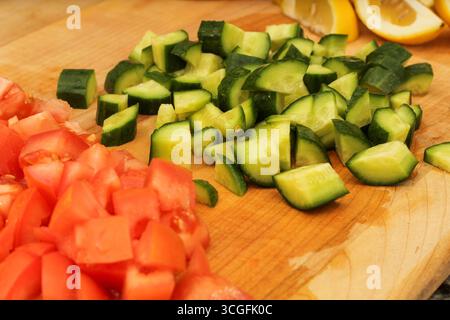 Geschnittene Gurken, Zitronen und Tomaten auf hölzernem Schneidebrett Stockfoto