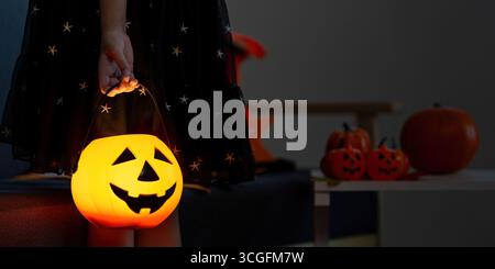 Halloween. Kind hält einen leuchtenden Kürbiseimer für Trick-or-Treatment. Stockfoto