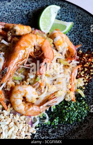 Blick von oben auf ein Pad thai Gericht mit Garnelen auf einer dunklen Keramikplatte Stockfoto