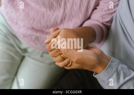 Glückliches Paar, das schöne Zeit zusammen in einem gemütlichen, modernen Zuhause verbringt. Sie unterhalten sich, trinken Kaffee, während die Frau auf einem Sofa sitzt und Stockfoto