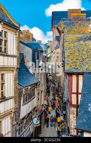 Malerischer Blick auf die enge, gewundene Hauptstraße Grand Rue von Mont-Saint-Michel mit den mittelalterlichen Fachwerkhäusern entlang der... Stockfoto