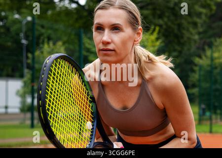 Konzentrierte Tennisspielerin auf dem Platz im Freien, bereit für das Spiel Stockfoto