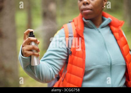 Schwarze Frau Mittleren Alters, Die Insektenschutzmittel Beim Wandern Im Freien Sprüht Stockfoto
