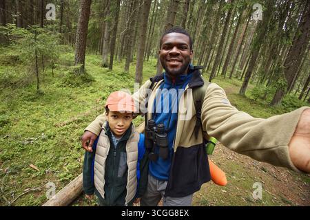 Porträt von Schwarzen und Jungen, die im Wald lächeln und wandern Stockfoto