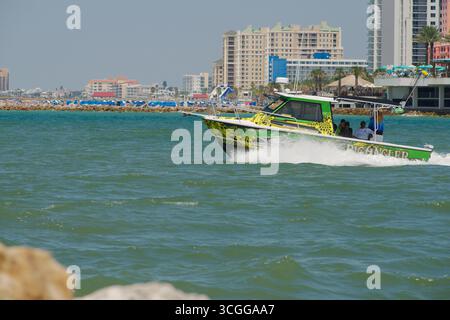 Buntes Motorboot auf türkisfarbenem Wasser in einer urbanen Umgebung am Meer Clearwater Beach, Florida, USA, nur redaktionelle Verwendung, 27. August, 2025. grün und gelb Stockfoto