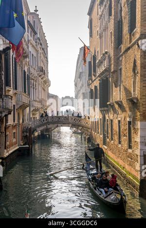 Venedig, Italien - 5. Februar 2025: Ein Gondoliere in traditioneller Kleidung fährt mit Touristen entlang eines Kanals in Venedig in der Nähe der Soupirs-Brücke, Ita Stockfoto