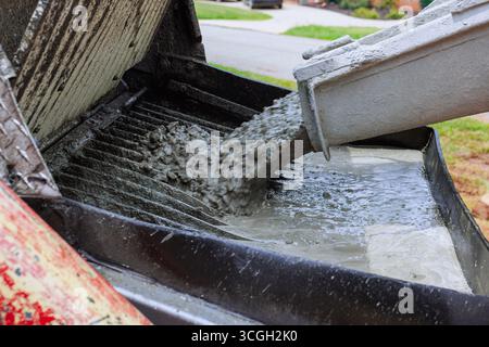 Der Arbeiter gießt während der Bauarbeiten auf der Baustelle zu Hause frischen Beton in den Mischer Stockfoto