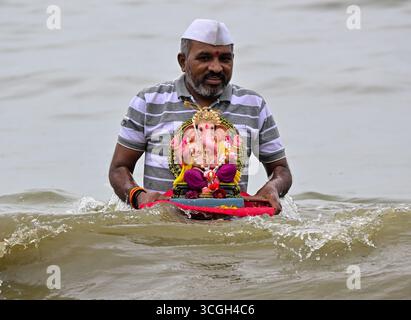 Ein Anhänger trägt ein Idol der hinduistischen Gottheit Ganesha, um während des Ganesh Chaturthi Festivals in Indien Mumbai.in in das Arabische Meer einzutauchen. Stockfoto