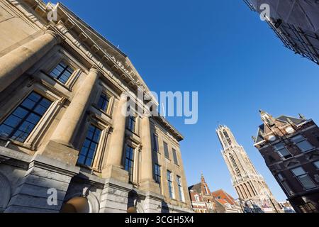 Ein dynamisches, flaches Bild zeigt die Architektur des Rathauses und den fernen Utrechter Dom vor einem weiten, klaren blauen Himmel Stockfoto
