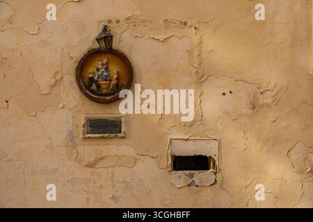 Gozo, Malta – 23. Juni 2021: Ein kleiner religiöser Wandschrein mit einer runden Gedenktafel, die die Madonna und das Kind unter einer Meta darstellt Stockfoto