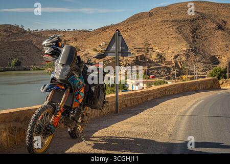 Yamaha Tenere 700 Abenteuer-Motorrad auf marokkanischer Bergstraße in der Nähe von Dorf und Fluss, perfekte Kulisse für Touren und Reisen im Gelände Stockfoto