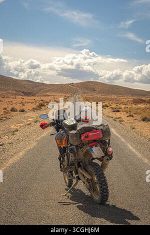 Yamaha Tenere 700 Abenteuerrad auf einer langen Wüstenstraße in Marokko, beladen für Touren mit malerischem Himmel und offener Landschaft Stockfoto