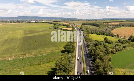 Autos auf der Autobahn m1 in der Nähe von Tata, Ungarn, umgeben von grünen Feldern Stockfoto
