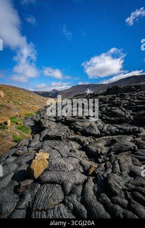 Islands vulkanische Landschaft entfaltet sich mit endlosen schwarzen Lavafeldern unter einem leuchtend blauen Himmel und fängt den rohen Geist des Landes aus Feuer und Eis ein Stockfoto