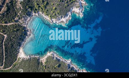 Blick aus der Vogelperspektive auf eine atemberaubende türkisfarbene Bucht, umgeben von üppigem Grün, treffen auf das tiefblaue Ägäische Meer und schaffen einen faszinierenden Kontrast der Farben in Tor Stockfoto