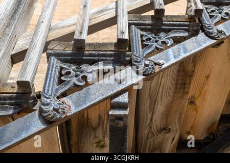Nahaufnahme einer antiken Treppe aus Eisen und Holz, die an der Außenseite einer beigefarbenen Ziegelmauer aus dem 19. Jahrhundert angebracht ist, bei hellem Sonnenlicht Stockfoto