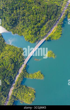 Blick aus der Vogelperspektive auf eine gewundene Straße und Brücke, die sich über türkisfarbenes Wasser zwischen grünen Inseln erstreckt. Stockfoto